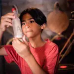Boy solving puzzle by examining a clue bottle in an escape room at Escapology.