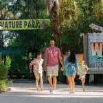 Family walking hand-in-hand at the entrance of Wild Florida Nature Park.