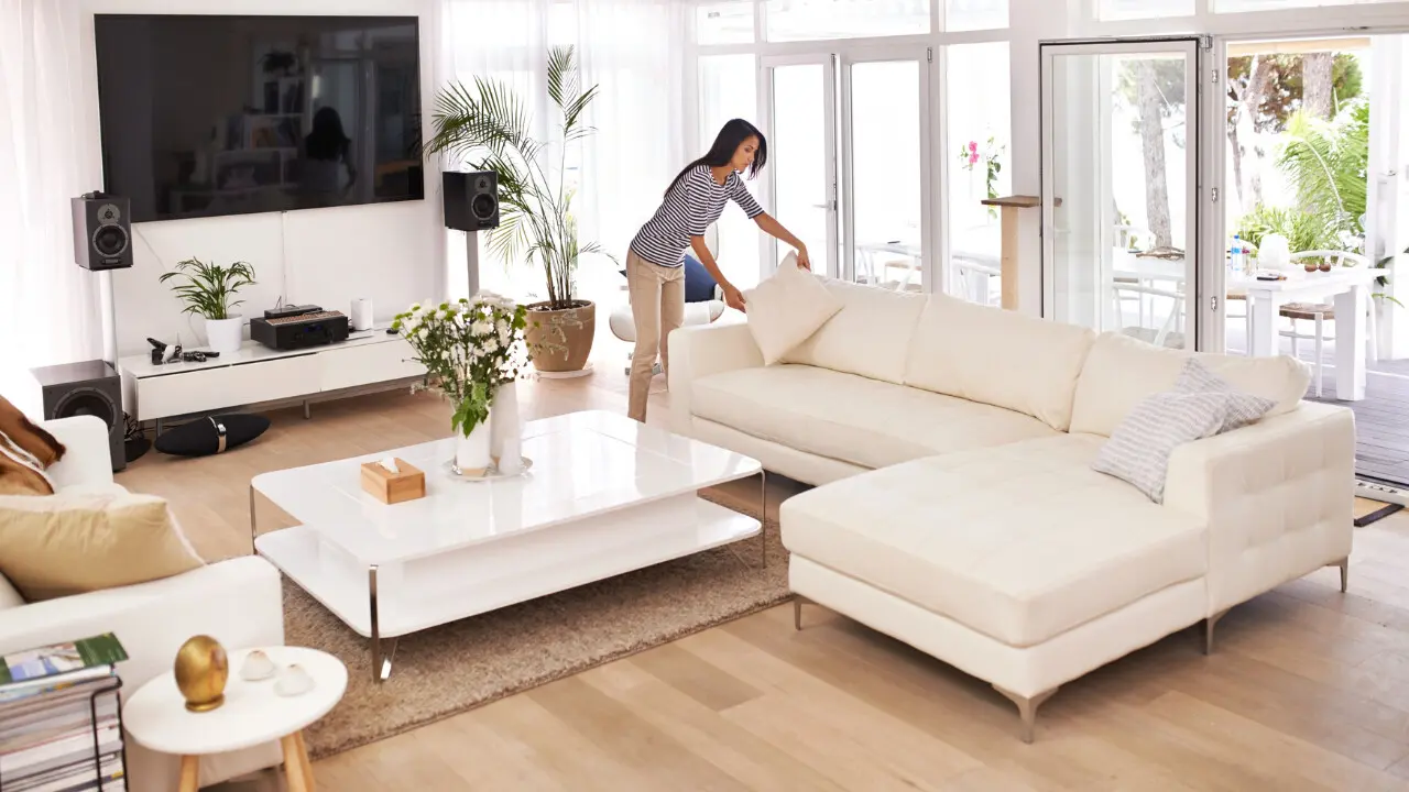 Woman tidying a bright, modern living room space.