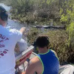 Tourists pointing at alligator during airboat adventure
